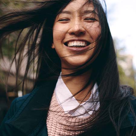 Woman outside on windy day smiling with dental implants in Louisville, KY