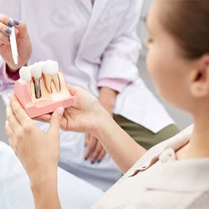 Dentist showing patient model of dental implant in Louisville, KY