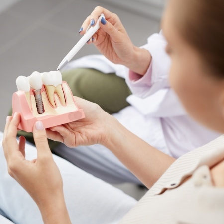 Dentist and patient looking at dental implant model