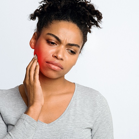 Woman with a toothache in Louisville touching her cheek