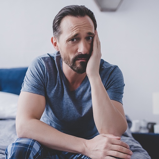 Man in need of emergency dentistry holding cheek in pain
