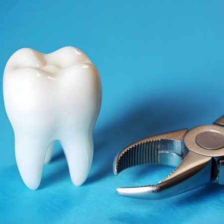 Tooth model next to dental forceps