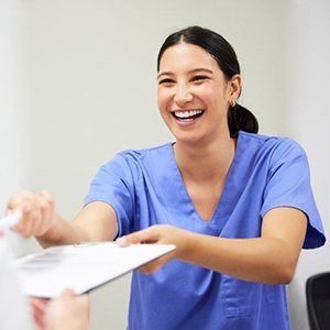 Dental team member handing clipboard to patient