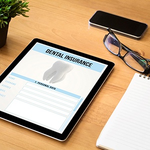 Tablet showing dental insurance form sitting on desk with other objects