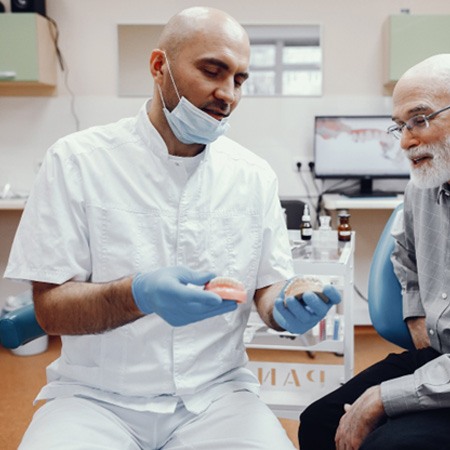 Dentist showing sample dentures to patient