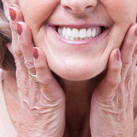 Nose to chin view of woman smiling with hands to her chin