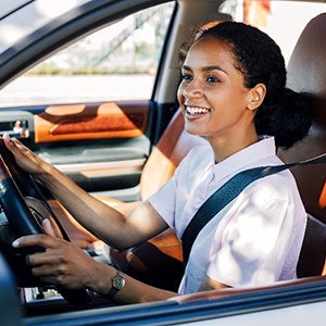 Woman in white shirt smiling while driving home