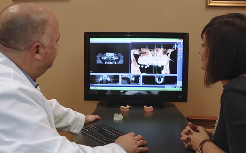 Periodontist and patient looking at digital dental impressions and x-rays