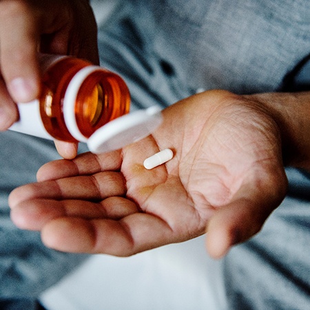 a person with a single pill in the palm of their hand