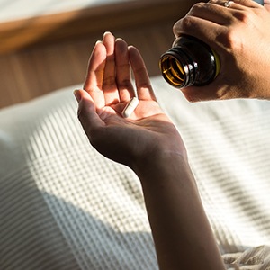 a person holding a pill bottle and pill