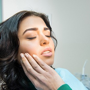 a dental patient holding her cheek 