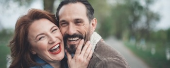 Man and woman smiling after dental implant tooth replacement