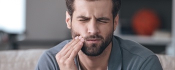 Man in need of emergency dentistry holding jaw in pain