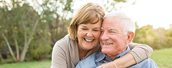 Man and woman with TeethXpress dental implant dentures smiling outdoors