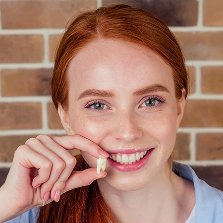 Woman holding up tooth after wisdom tooth extraction