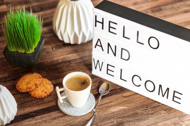 Hello and welcome sign on table with coffee and plant