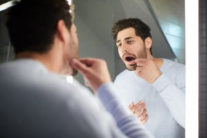 man looking at his gums in the mirror 