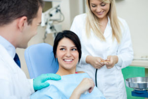 Male dentist, his assistant and smiling female patient 
