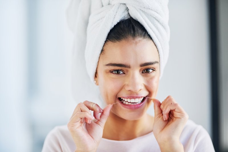 woman flossing her dental implants in Louisville