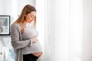 Pregnant woman smiling and holding belly. 