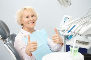 Senior woman in dental chair giving two thumbs up