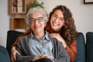 Woman posing with her older parent, both happy and smiling.
