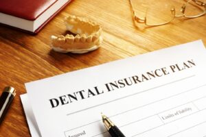 Dental insurance paperwork and nearby tooth mold